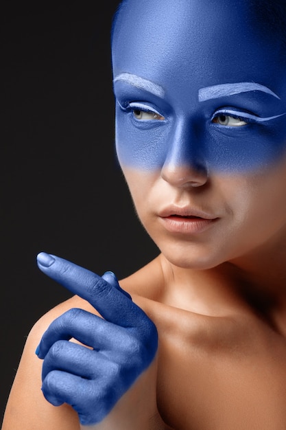 Free photo portrait of a woman who is posing covered with blue paint