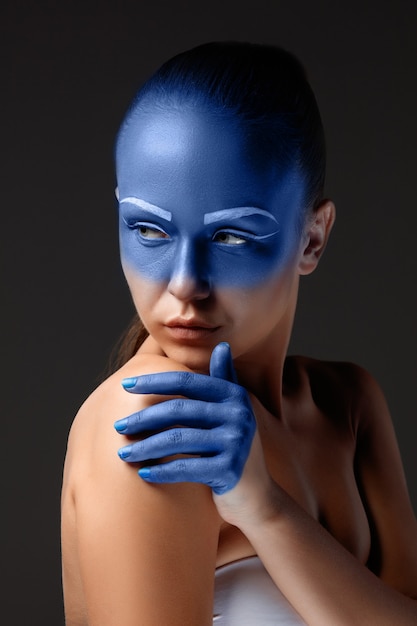 Free photo portrait of a woman who is posing covered with blue paint