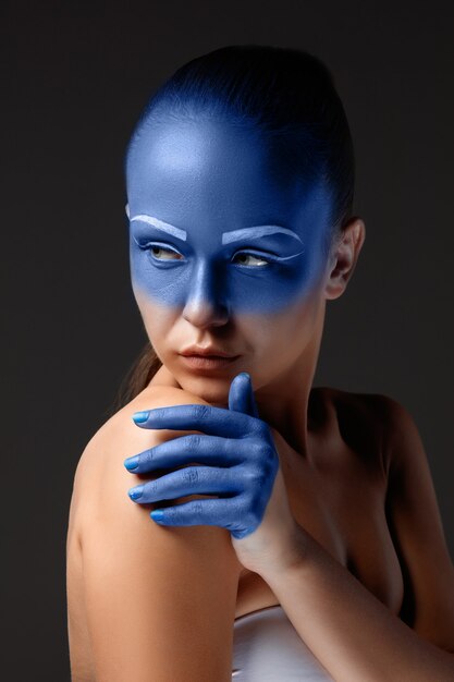 Portrait of a woman who is posing covered with blue paint