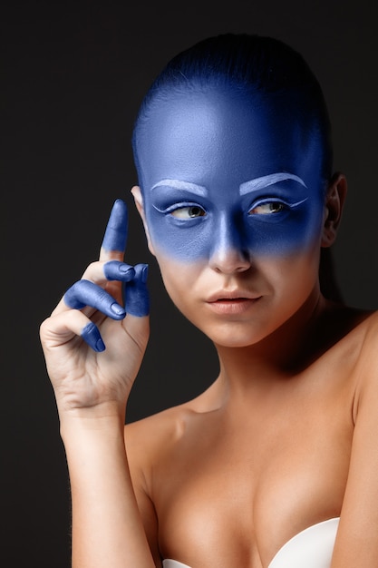 Portrait of a woman who is posing covered with blue paint