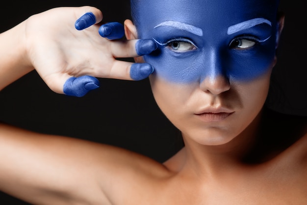 Free photo portrait of a woman who is posing covered with blue paint