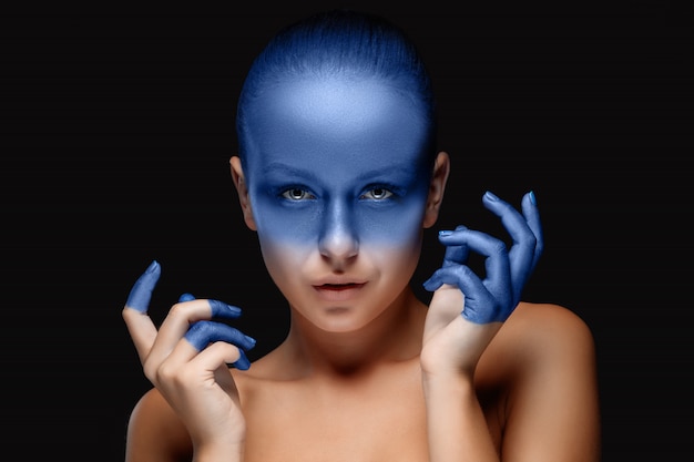 Free photo portrait of a woman who is posing covered with blue paint