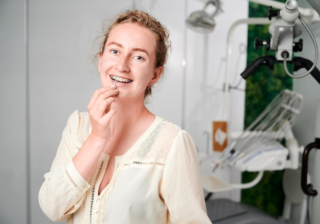 Free photo portrait of woman with braces demonstrating interdental brushing