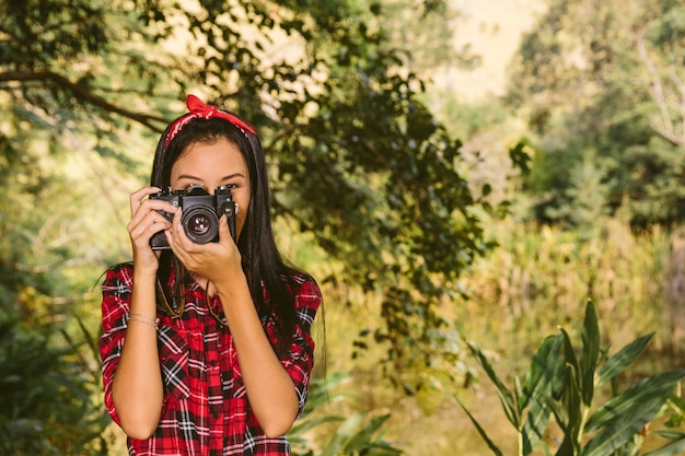 Portrait of a woman with camera in forest