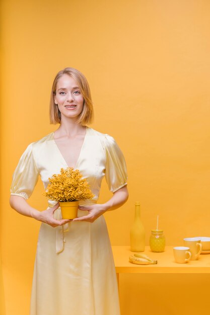 Portrait of woman with a flower pot in a yellow scene