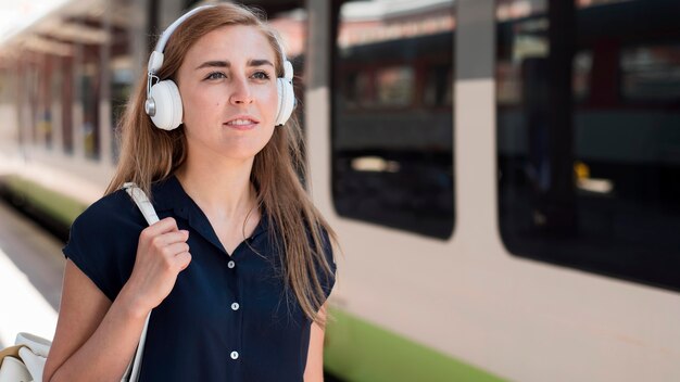 Portrait of woman with headphones in train station