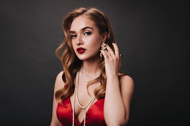 Portrait of woman with red lips looks into camera on black background