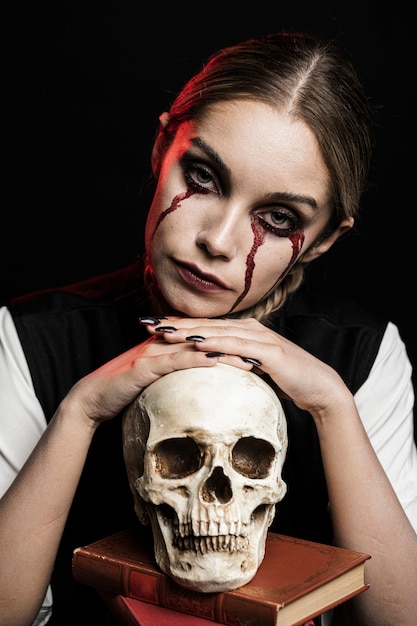 Free photo portrait of woman with skull and books