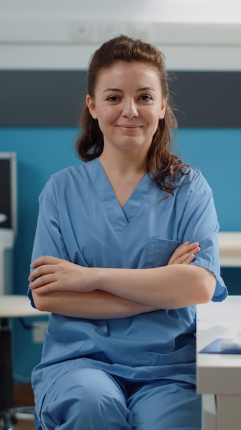 Free photo portrait of woman working as medical assistant at desk in doctors office. nurse looking at camera and smiling while preparing for work on computer. healthcare specialist in uniform