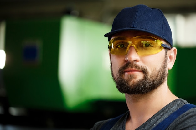 Portrait of worker in overalls, steel factory background.