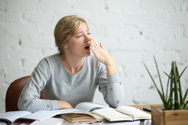 Portrait of a yawning student girl at the desk