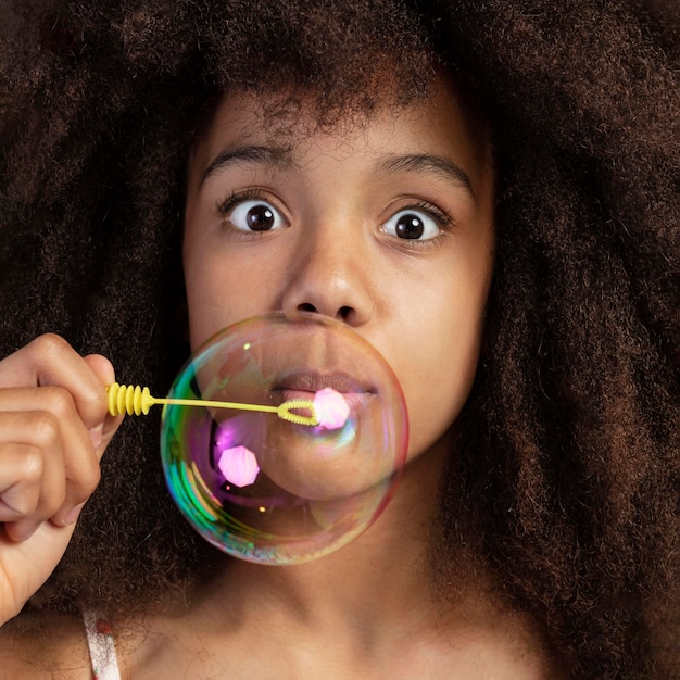 Portrait of young adorable girl posing while playing with soap bubbles