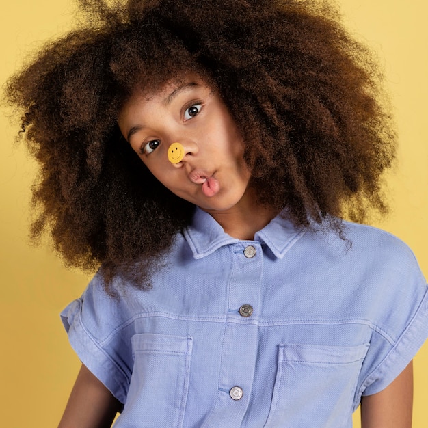 Free photo portrait of young adorable girl posing with emoji stickers on her face