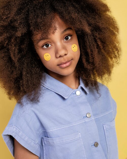 Portrait of young adorable girl posing with emoji stickers on her face