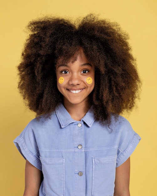 Free photo portrait of young adorable girl posing with emoji stickers on her face