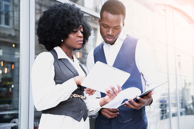 Portrait of a young african businesswoman showing something on digital tablet to her colleague