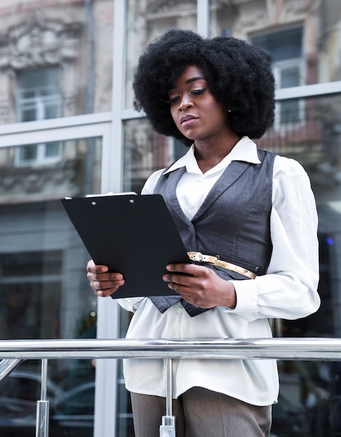 Portrait of a young african businesswoman standing in front of railing holding clipboard