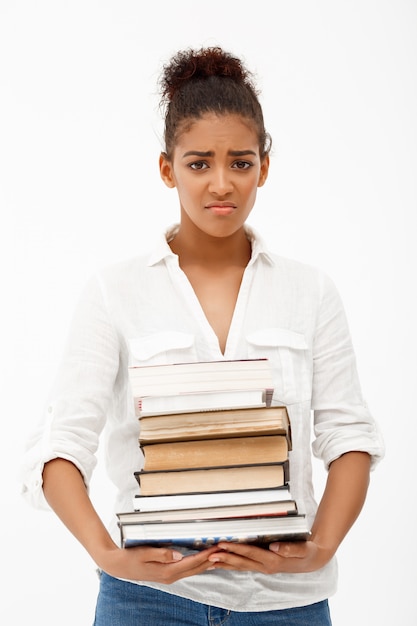 Portrait of young african girl with books over white wall