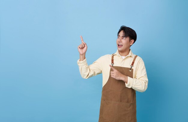 Portrait young asian barista man wearing apron standing and pointing finger advertising