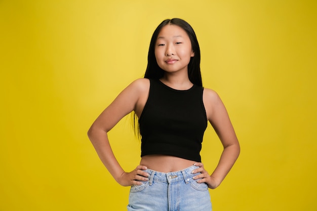 Free photo portrait of young asian girl isolated on yellow studio