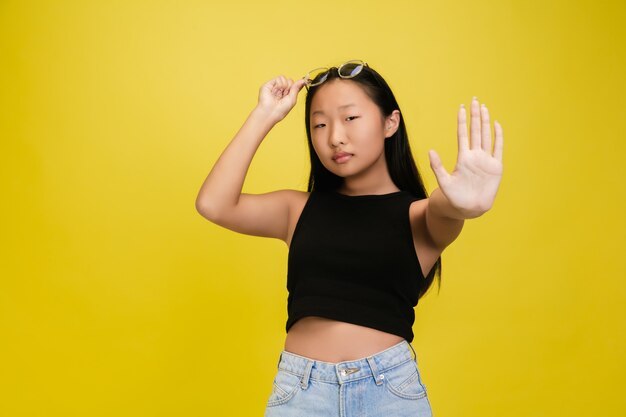 Portrait of young asian girl isolated on yellow studio