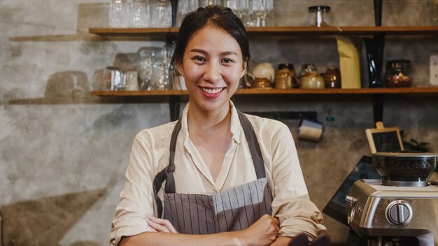 Portrait young Asian woman barista feeling happy smiling at urban cafe.