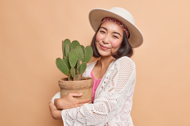 Portrait of young Asian woman embraces potted cactus