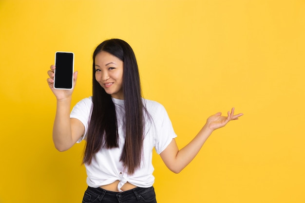 Portrait of young asian woman isolated on yellow wall