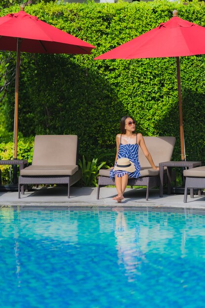 Portrait young asian woman relax smile happy around outdoor swimming pool in hotel resort with sea ocean view