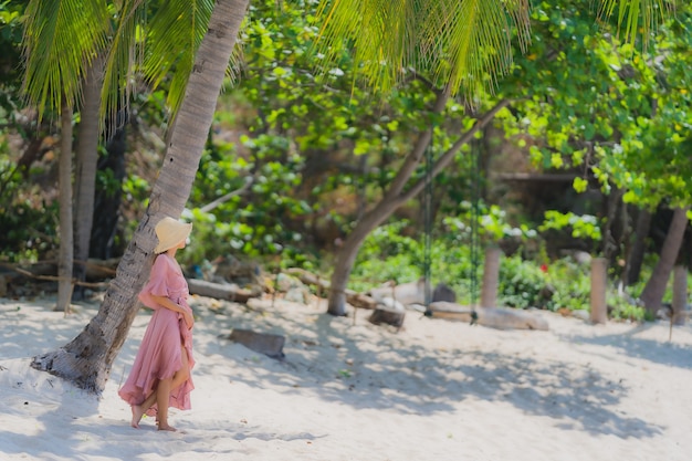 Portrait young asian woman smile happy around beach sea ocean with coconut palm tree for holiday vacation