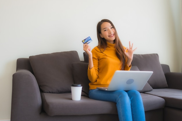 Portrait young asian woman using laptop computer with smart mobile phone and credit card for online shopping