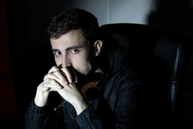 Portrait of young attractive man with earphones. Dark-haired man in casual clothes looking at camera, holding hands near face. Portrait concept