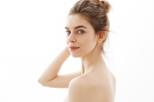 Portrait of young attractive tender naked woman with bun over white background.