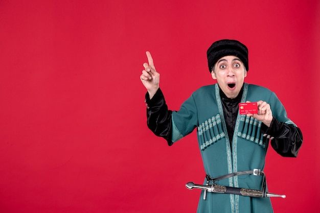 Free photo portrait of young azeri man in traditional costume holding credit card on red