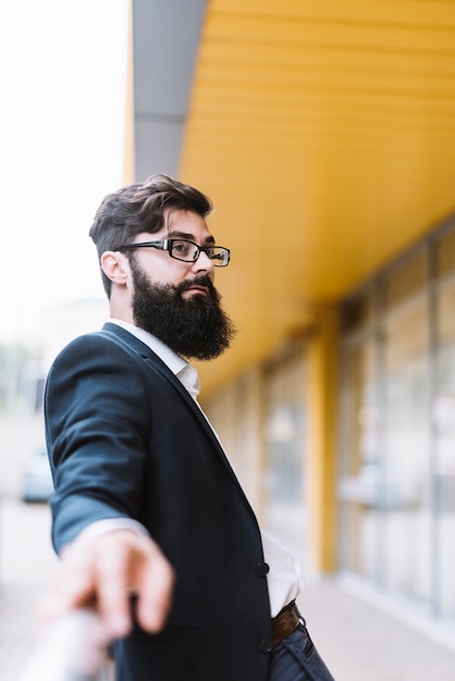 Free photo portrait of young beard businessman with black eyeglasses looking away