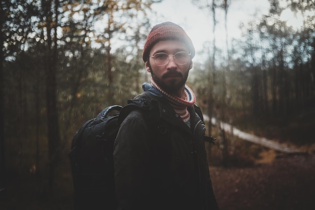 Free Photo portrait of young bearded hipster with backpack in the autumn forest.