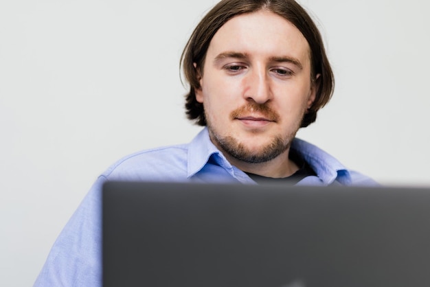 Portrait of young bearded man smiling and using laptop while sitting on sofa at home