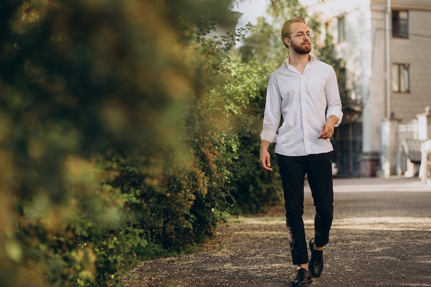 Portrait of young bearded man wearing spectacles and walking in park