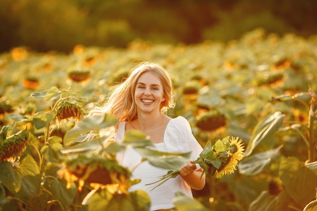 Portrait of young beautiful blonde woman in sunflowers field in back light. Summer countryside concept.Woman and sunflowers. Summer light. Outdoor beauty.