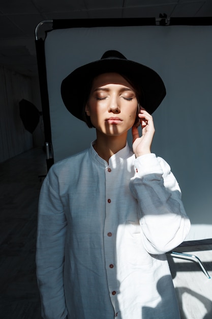 Portrait of young beautiful brunette girl in black hat.