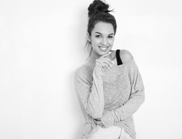 Portrait of young beautiful brunette woman girl model with nude makeup in summer clothes posing near wall. 