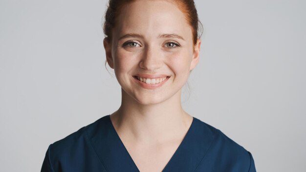 Portrait of young beautiful female doctor happily looking in camera and smiling over white background