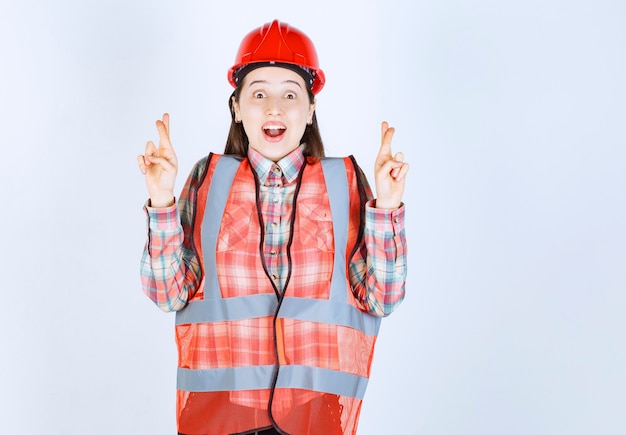 Portrait of young beautiful female engineer in helmet giving secret sign. 