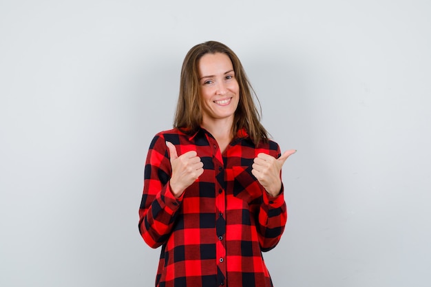 Portrait of young beautiful female pointing to opposite directions in casual shirt and looking merry front view