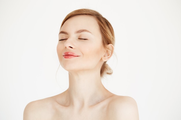 Portrait of young beautiful girl with clean fresh skin isolated on white background. Closed eyes. Beauty and health lifestyle.