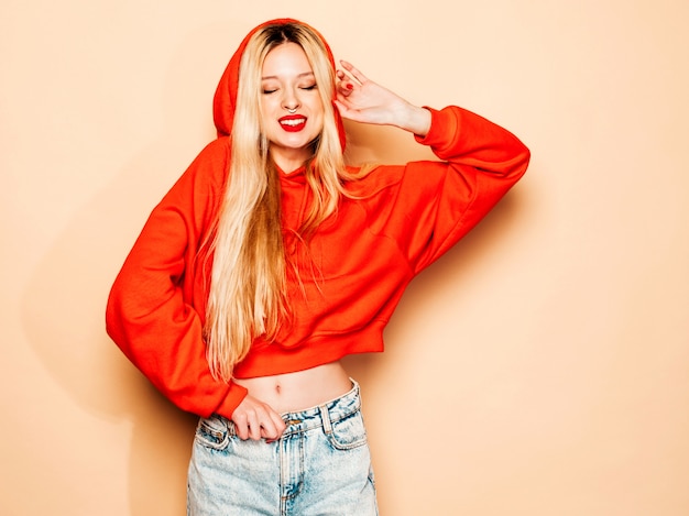 Free photo portrait of young beautiful hipster bad girl in trendy red  hoodie and earring in her nose.  positive model having fun