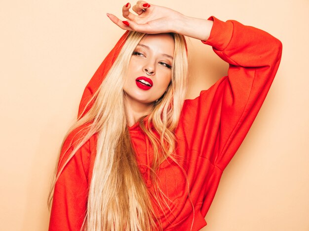 Portrait of young beautiful hipster bad girl in trendy red  hoodie and earring in her nose.  Positive model