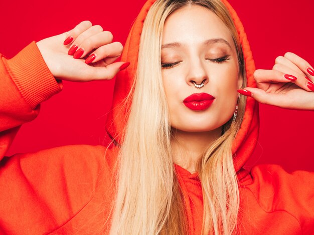 Portrait of young beautiful hipster bad girl in trendy red  hoodie and earring in her nose.  Positive model