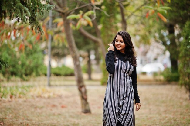 Portrait of young beautiful indian or south asian teenage girl in dress posed at autumn park in Europe