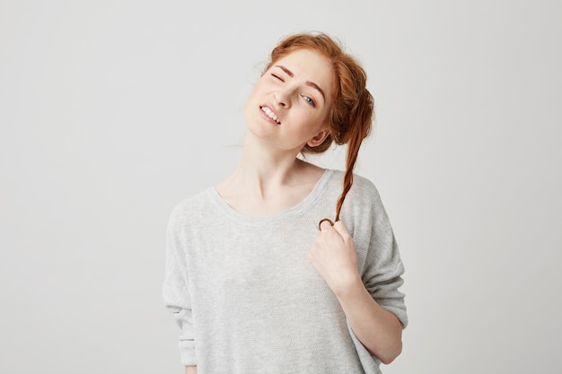 Free photo portrait of young beautiful redhead girl untie bun touching hair .